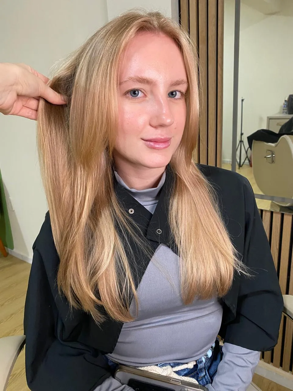 Cliente com cabelo longo e liso em tom acobreado claro, sendo finalizada no studio